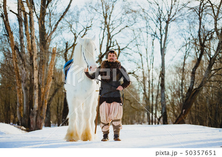 Man in suit of ancient warrior walking with the big white horse 50357651