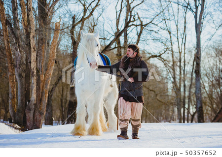 Man in suit of ancient warrior walking with the big white horse 50357652