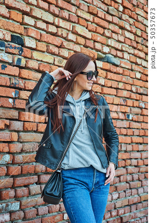 Young redhead woman posing near the brick wall 50357673