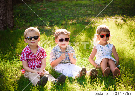 Smiling kids at the garden in sunglasses Smiling kids at the garden in sunglasses 50357765