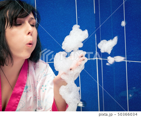 Woman blowing bubbles in bathroom Woman blowing bubbles in bathroom 50366034