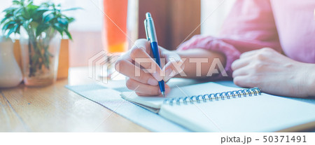 Woman hand is writing on a notepad with a pen. 50371491