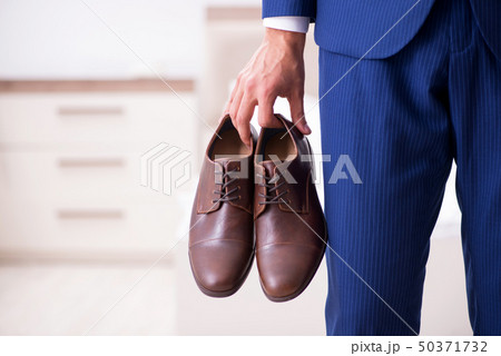Young handsome businessman choosing shoes at home Young handsome businessman choosing shoes at home 50371732