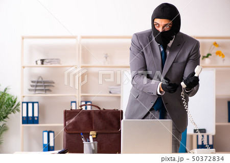 Male gangster stealing information from the office  50372834