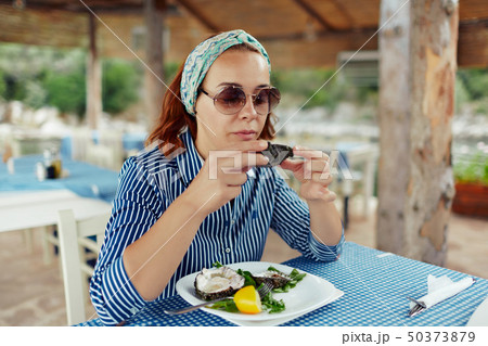 Young woman eating oyster in an outdoor restaurant 50373879