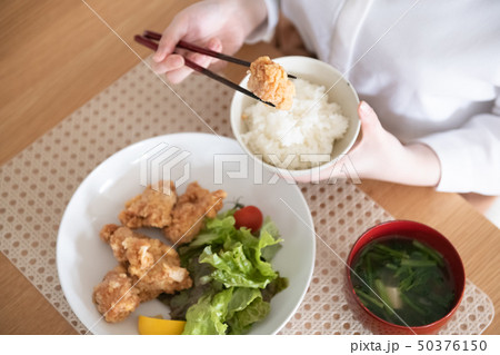 鶏の唐揚げを食べる若い女性の手元 50376150