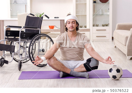 Injured young man doing exercises at home Injured young man doing exercises at home 50376522