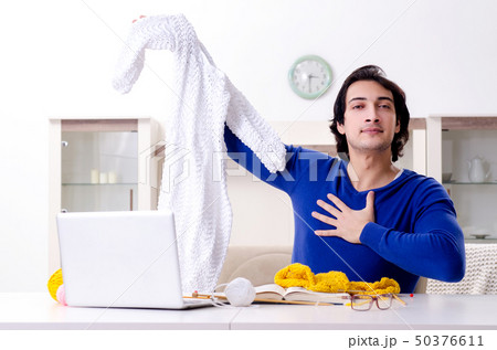 Young good looking man knitting at home Young good looking man knitting at home 50376611