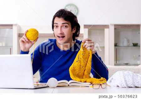 Young good looking man knitting at home Young good looking man knitting at home 50376623