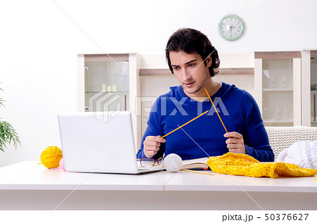 Young good looking man knitting at home Young good looking man knitting at home 50376627
