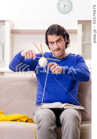 Young good looking man knitting at home Young good looking man knitting at home 50376670