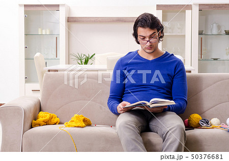 Young good looking man knitting at home Young good looking man knitting at home 50376681