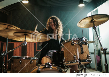 Woman playing drums during music band rehearsal 50387088