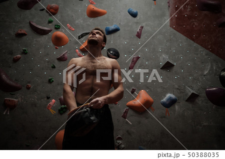 Athletic man using chalk before climbing in a bouldering gym Athletic man using chalk before climbing in a bouldering gym 50388035