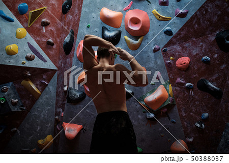 Athletic man stretching before climbing in a bouldering gym 50388037