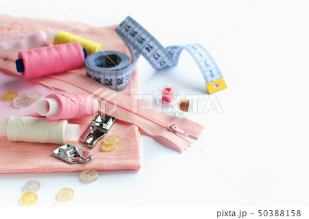 Sewing accessories and fabric on a white background. Pink fabric, sewing threads, needle, buttons Sewing accessories and fabric on a white background. Pink fabric, sewing threads, needle, buttons 50388158