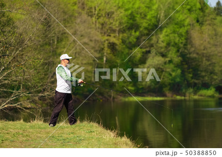 Fisherman with a spinning rod catching fish Fisherman with a spinning rod catching fish 50388850