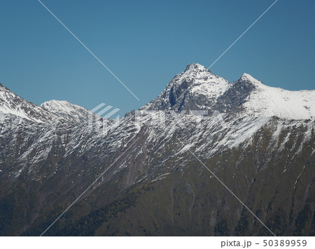 The snowy peaks of the mountains on a clear day The snowy peaks of the mountains on a clear day 50389959
