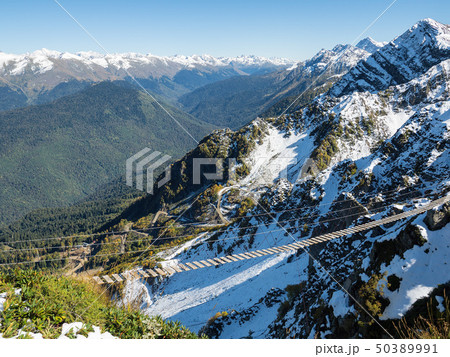 Suspension footbridge in the high snowy mountains. Suspension footbridge in the high snowy mountains. 50389991