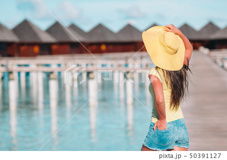 Woman with yellow hat relaxing at swimming pool in exotic resort 50391127