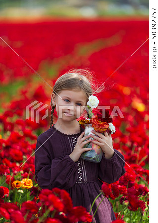 girl in a burgundy summer dress picking flowers in the meadow 50392757