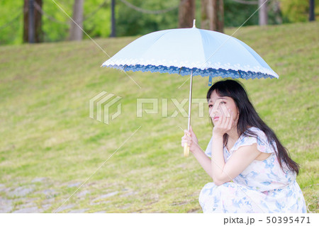 青い傘を差す花柄ワンピースの女性 50395471