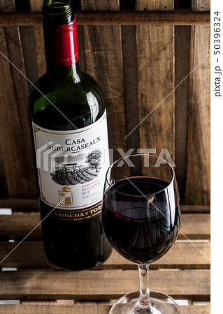 木の背景で赤ワインのボトルとワイングラスがオシャレにおいてあるワインバーの写真素材