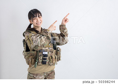 白背景に迷彩服の女の子が笑顔で両手で指を指しているサバイバルゲーム 50398244