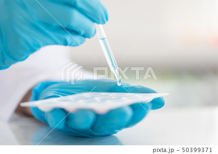 Scientist dropping liquid to sample tray.. Scientist dropping liquid to sample tray.. 50399371