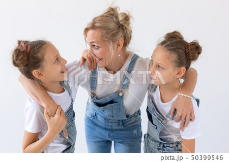 Family, sisters and love concept - Mother hugging two twin daughters over white background 50399546