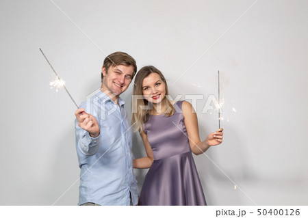 Party, family and holidays concept - young couple looking to sparklers on white background 50400126