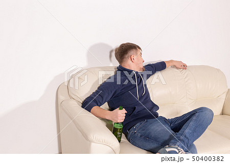 Depression and alcoholism concept - Aggressive male alcoholic sitting on the sofa Depression and alcoholism concept - Aggressive male alcoholic sitting on the sofa 50400382