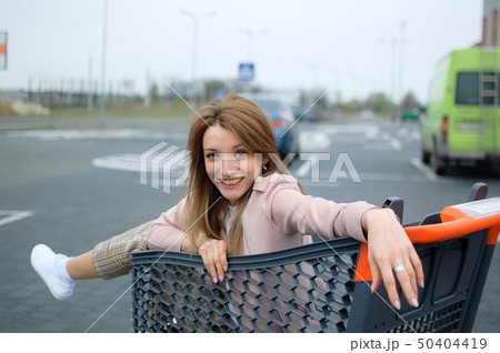 Beautiful girl in the trolley near the supermarket. Autdoor 50404419