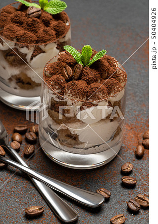 two portions Classic tiramisu dessert in a glass on dark concrete background two portions Classic tiramisu dessert in a glass on dark concrete background 50404926