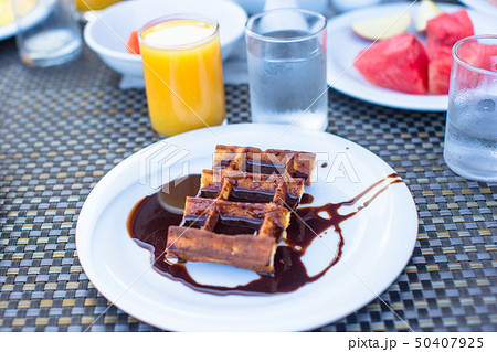 Delicious waffles with chocolate, water and juice served for breakfast at outdoor cafe Delicious waffles with chocolate, water and juice served for breakfast at outdoor cafe 50407925