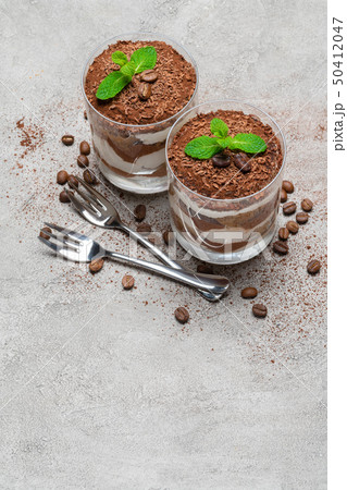 two portions Classic tiramisu dessert in a glass on concrete background two portions Classic tiramisu dessert in a glass on concrete background 50412047