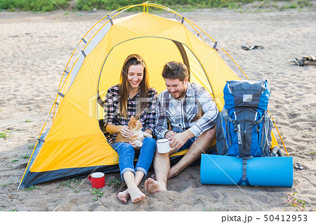 Pet, summer tourism and nature concept - young couple sitting with cat near a tent 50412953