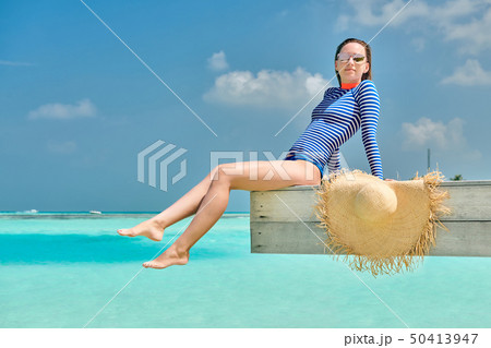 Woman sitting at beach jetty Woman sitting at beach jetty 50413947