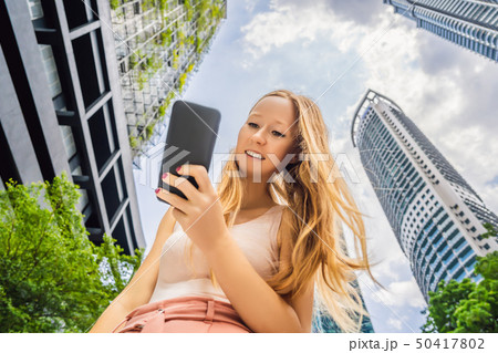 woman using map app on smartphone on the background of skyscrapers 50417802