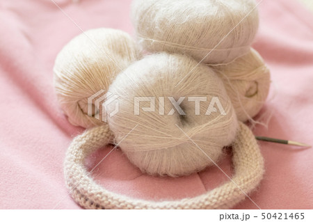 A coil of soft beige wool for knitting on a pink background 50421465