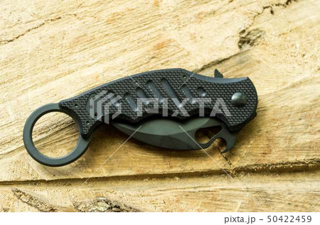 Tactical knife in a folded position on a wooden. Tactical knife in a folded position on a wooden. 50422459