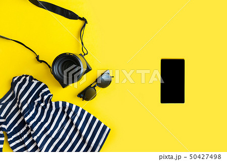 Flat lay traveler accessories on yellow background with blue dress, camera and sunglasses. Summer 50427498