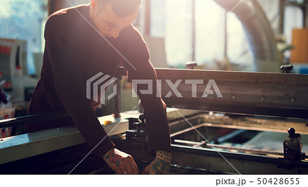 Man controls wide industrial printer in workshop 50428655
