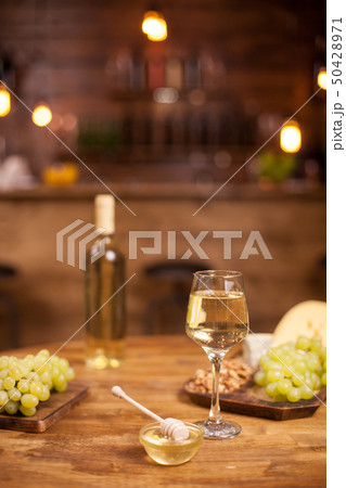 Cheese plate served with a glass of white and wolnuts in a vintage restaurant over a wooden table 50428971