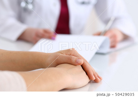 Unknown doctor woman consulting patient while filling up an application form at the desk in hospital 50429035