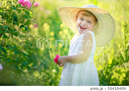 A little girl wearing flower yellow dress with white hat and stand in the yellow flower field of A little girl wearing flower yellow dress with white hat and stand in the yellow flower field of 50430409