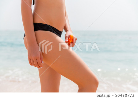 Young girl is applying sunblock form the spray on Young girl is applying sunblock form the spray on 50430772