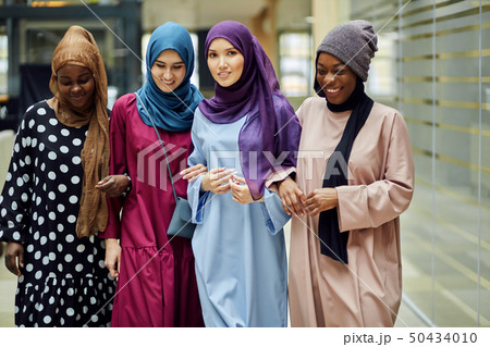 Multiracial group of muslim women dressed in national clothes posing in group 50434010