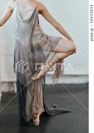 Ballet dancer with floating fabric flexing her leg aside, warm-up before dance 50435633