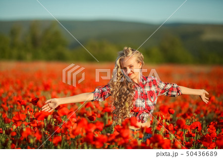 Young blonde in a red shirt in the poppy flower field. Young blonde in a red shirt in the poppy flower field. 50436689